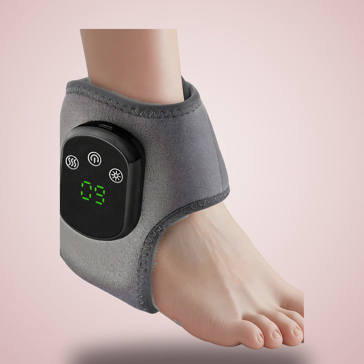 Snando Heated Ankle Wrap worn on the ankle, control pod with green display, on warm blush background