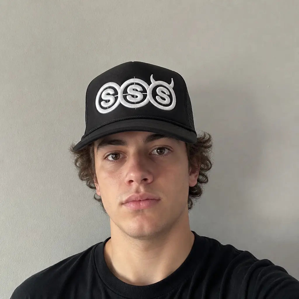 Young man wearing the black SSS trucker hat, front view, embroidery fully visible
